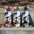 Three Loaded Ballona Orca longboards with a matching black, white, and gray abstract wave pattern are lined up on a concrete ledge outdoors. The boards feature different colored wheels: pink, yellow, and light blue.