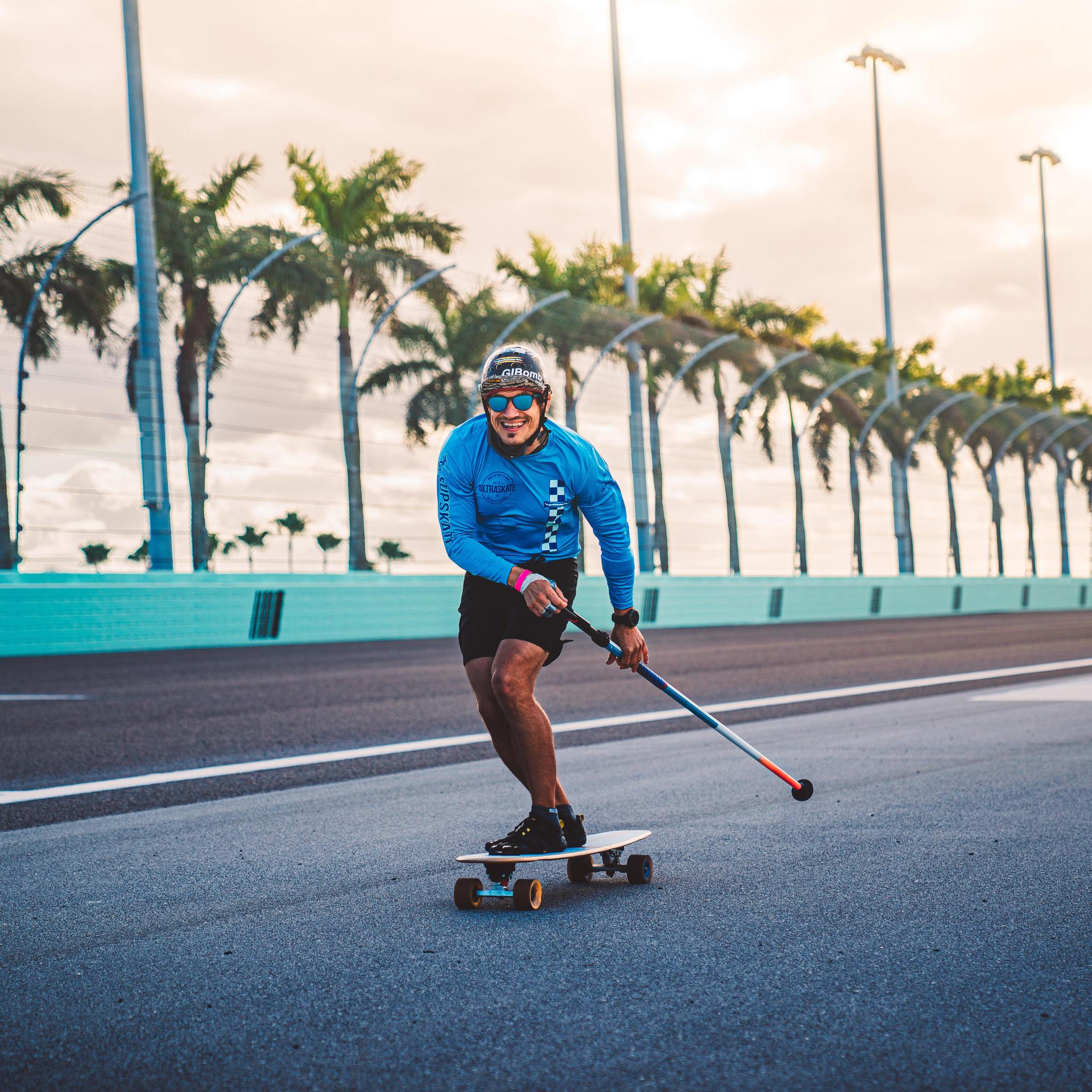 Person skateboarding on a palm tree-lined road during sunset