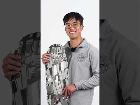 Smiling person in a grey shirt holding a skateboard.